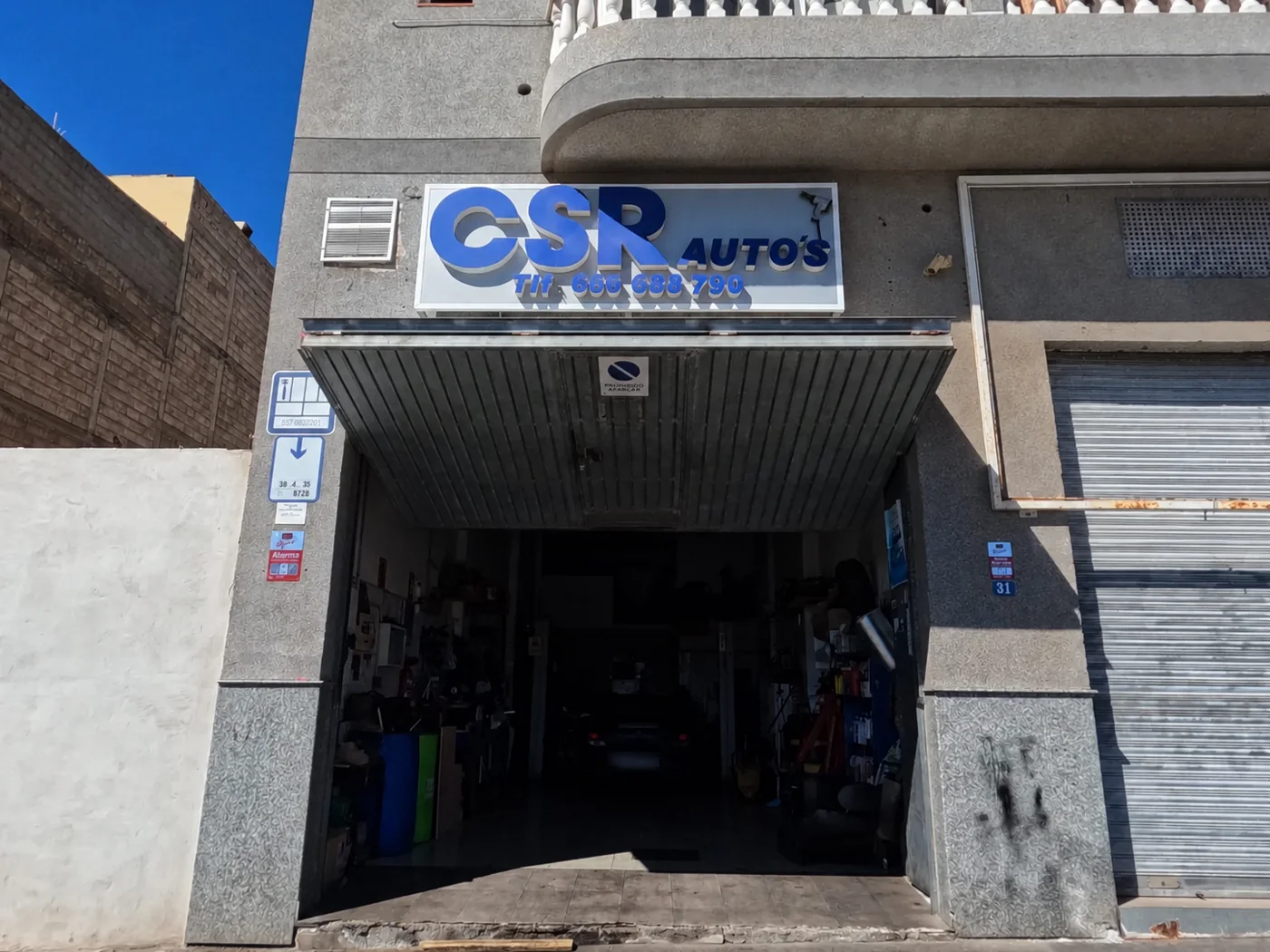 Entrada de CSR Autos en Calle Tilena 31, con el rótulo del taller sobre la puerta.